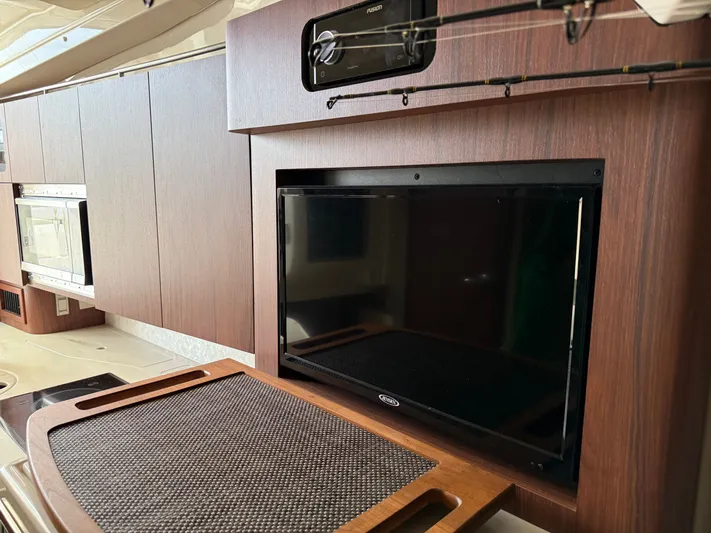  Yacht Photos Pics 2025 Grady-White Express 330 interior with TV, microwave, and wooden cabinetry.