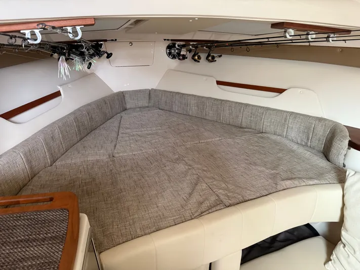  Yacht Photos Pics 2025 Grady-White Express 330 cabin interior with fishing rods and cushioned seating.
