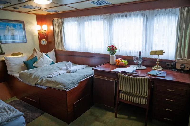 Sanssouci Star Yacht Photos Pics Luxurious cabin interior on 1982 Custom Displacement Twin Screw yacht, featuring bed, desk, and decor.