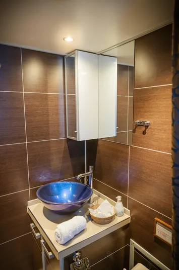 Sanssouci Star Yacht Photos Pics Luxurious bathroom with blue vessel sink, modern fixtures, and elegant brown tile walls.