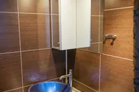 Luxurious bathroom with blue vessel sink, modern fixtures, and elegant brown tile walls.