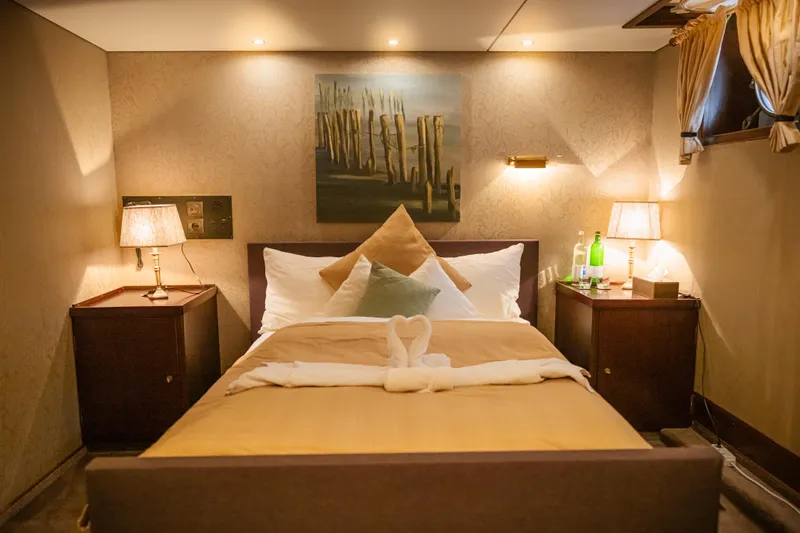 Sanssouci Star Yacht Photos Pics Cozy bedroom with elegant decor, warm lighting, and a neatly made bed on a 1982 Custom Displacement Twin Screw.