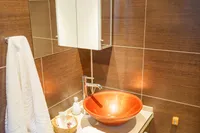 Luxurious bathroom with modern fixtures, vessel sink, and elegant brown tile design.