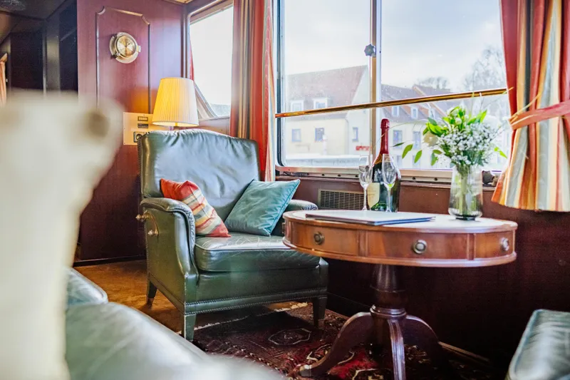 Sanssouci Star Yacht Photos Pics Luxurious 1982 Custom Displacement Twin Screw yacht interior with leather chair, table, and window view.