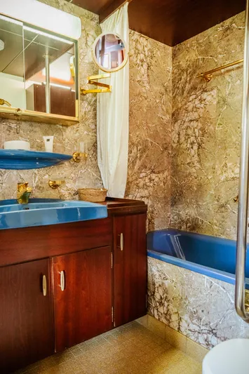 Sanssouci Star Yacht Photos Pics Vintage 1982 bathroom with blue fixtures, marble walls, and wooden cabinetry on a custom vessel.