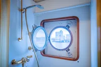 Shower area with brass fixtures and porthole window on a 1982 Custom Displacement Twin Screw.