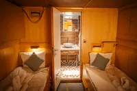 Twin cabin interior with wooden decor and ensuite bathroom on a 1982 Custom Displacement Twin Screw yacht.
