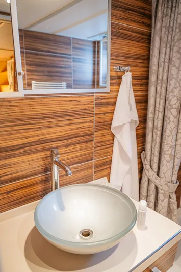 Sanssouci Star Yacht Photos Pics Modern bathroom with glass vessel sink, wooden wall paneling, and elegant towel setup.