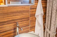 Modern bathroom with glass vessel sink, wooden wall paneling, and elegant towel setup.