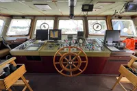 Bridge of 1982 Custom Displacement Twin Screw ship with navigation equipment and wooden wheel.