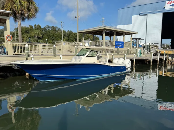 Giddy Up Yacht Photos Pics 2019 Scout 355 LXF CC boat docked at marina, reflecting on calm water.