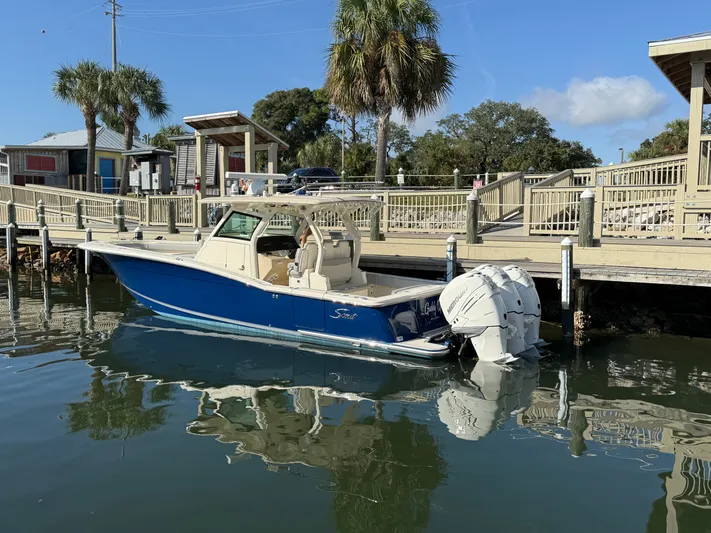 Giddy Up Yacht Photos Pics 2019 Scout 355 LXF CC boat docked by a wooden pier under clear blue skies.