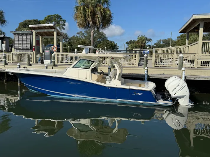 Giddy Up Yacht Photos Pics 2019 Scout 355 LXF CC boat docked, featuring sleek blue design and powerful Mercury engines.