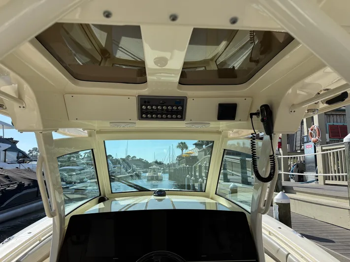 Giddy Up Yacht Photos Pics Interior view of 2019 Scout 355 LXF CC boat cockpit with control panel and marina background.