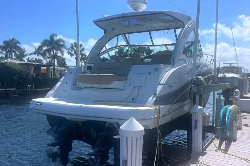  Yacht Photos Pics 2014 Cruisers Yachts 380 Express on lift at marina, surrounded by palm trees.