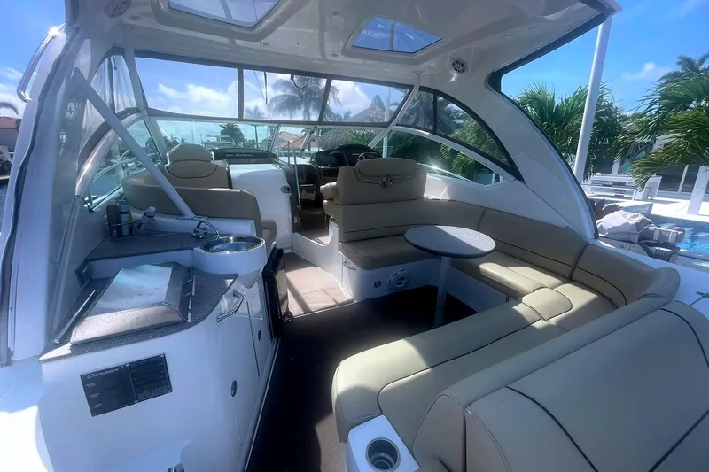  Yacht Photos Pics 2014 Cruisers Yachts 380 Express interior with seating, table, and kitchenette under a sunny sky.