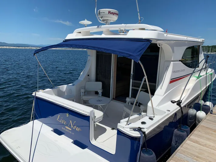 Live Now Yacht Photos Pics 2012 Silverton 33 Sport Coupe docked, featuring a blue canopy and spacious deck.