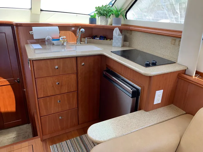Live Now Yacht Photos Pics 2012 Silverton 33 Sport Coupe yacht kitchen with wood cabinetry, sink, stove, and mini fridge.