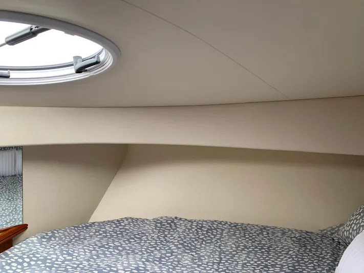 Live Now Yacht Photos Pics Interior cabin of 2012 Silverton 33 Sport Coupe with circular window and patterned bedding.