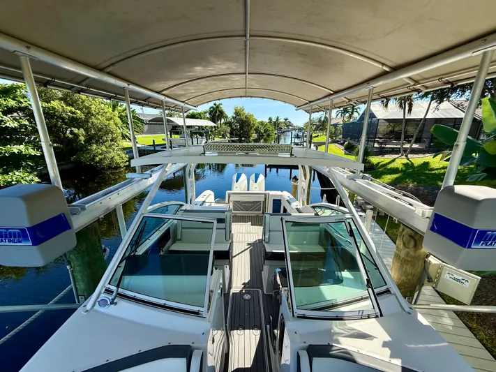  Yacht Photos Pics 2019 Blackfin 272 DC boat docked under canopy, surrounded by lush greenery.