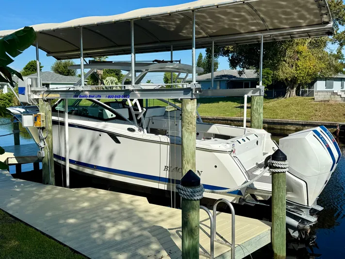  Yacht Photos Pics 2019 Blackfin 272 DC boat on lift, docked by a canal under a canopy.