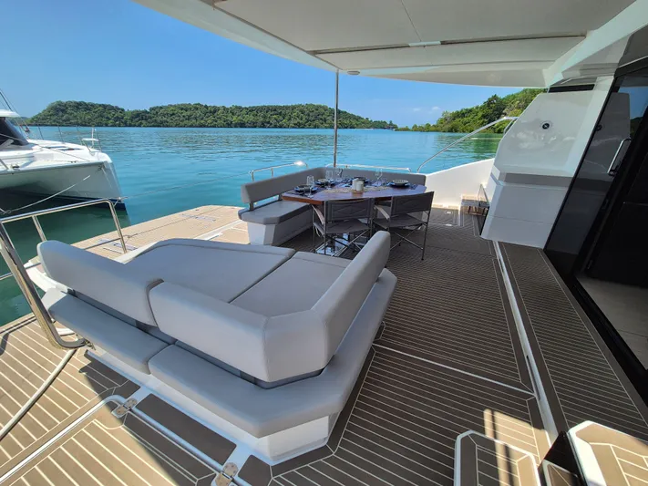  Yacht Photos Pics 2024 Leopard 53 Powercat yacht with luxurious deck seating and dining area, overlooking serene waters.