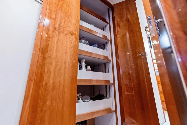 Sonny Boy Yacht Photos Pics Wooden storage shelves inside a 2004 Bertram 570 yacht, featuring various items neatly organized.