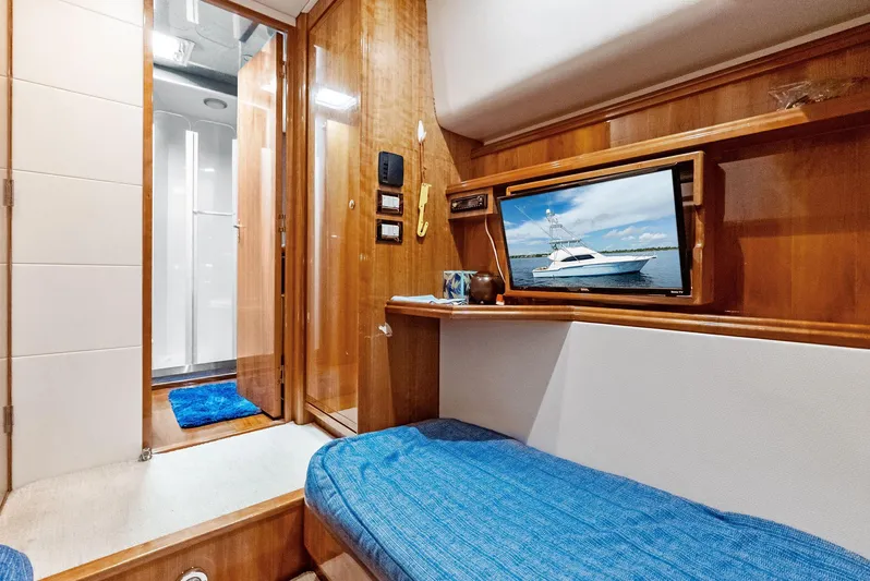Sonny Boy Yacht Photos Pics Interior of 2004 Bertram 570 yacht with wooden paneling and blue bedding.