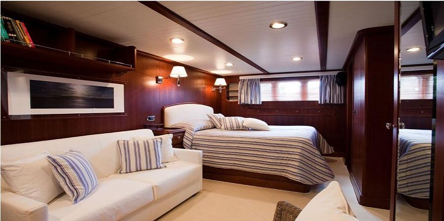 Luxurious cabin interior of 2005 Explorer Trawler 33m with cozy bed and sofa.