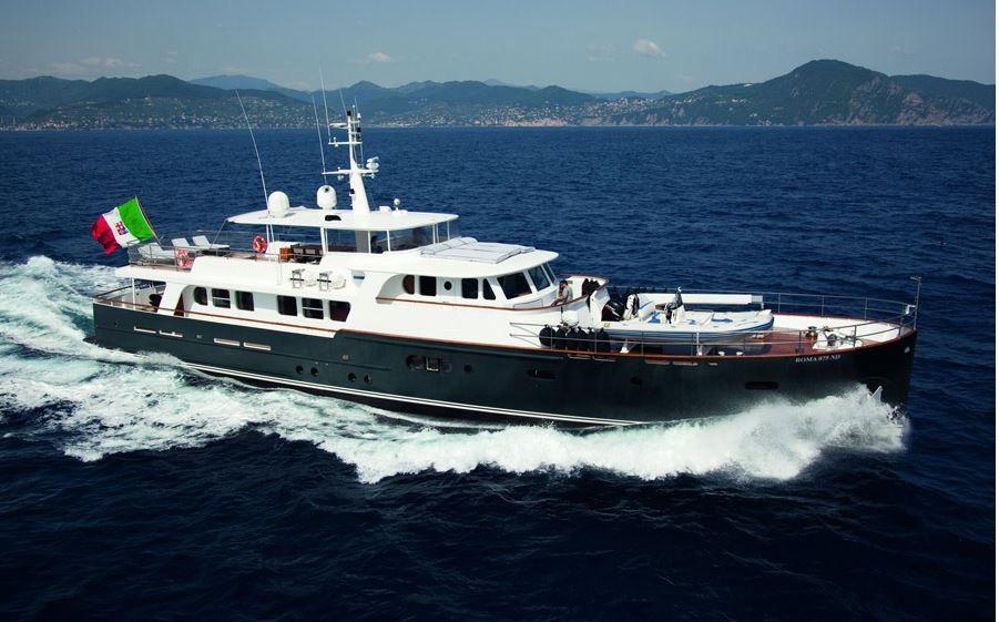 Explorer Trawler 33m yacht cruising on the ocean, 2005 model, with scenic coastline backdrop.
