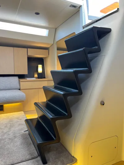  Yacht Photos Pics Modern interior of 2004 Vismara V78 yacht with sleek black staircase and cozy seating area.