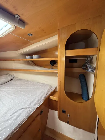  Yacht Photos Pics Interior cabin of 2006 Fountaine Pajot Bahia 46 catamaran, featuring wooden shelves and cozy bedding.