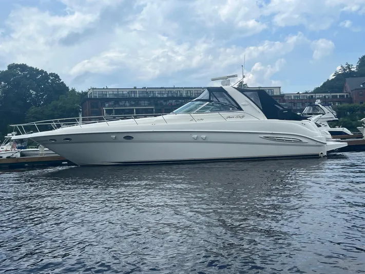Phantom Yacht Photos Pics 2000 Sea Ray 460 Sundancer yacht docked on a calm river under a partly cloudy sky.