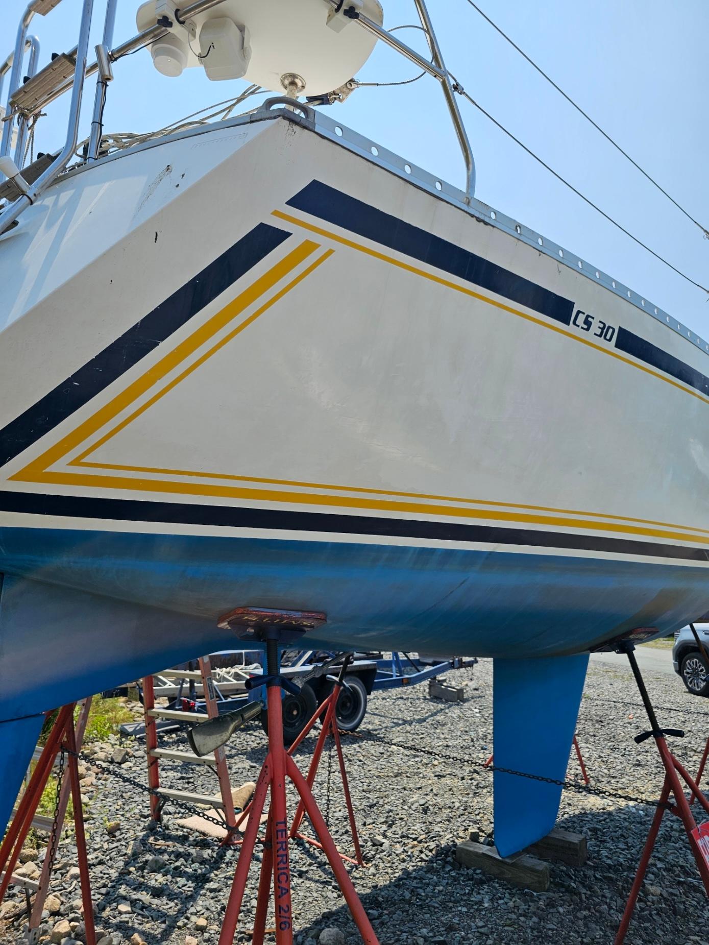 1987 CS 30 sailboat on stands, featuring blue and yellow stripes.
