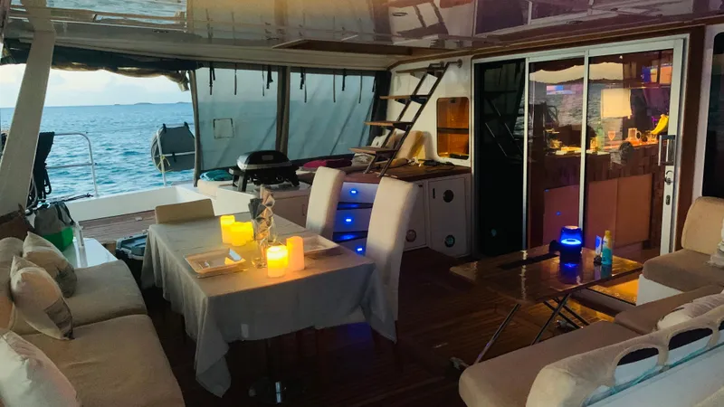 Talon Yacht Photos Pics Luxurious Sunreef 62 yacht interior with cozy seating, dining area, and ocean view at sunset.
