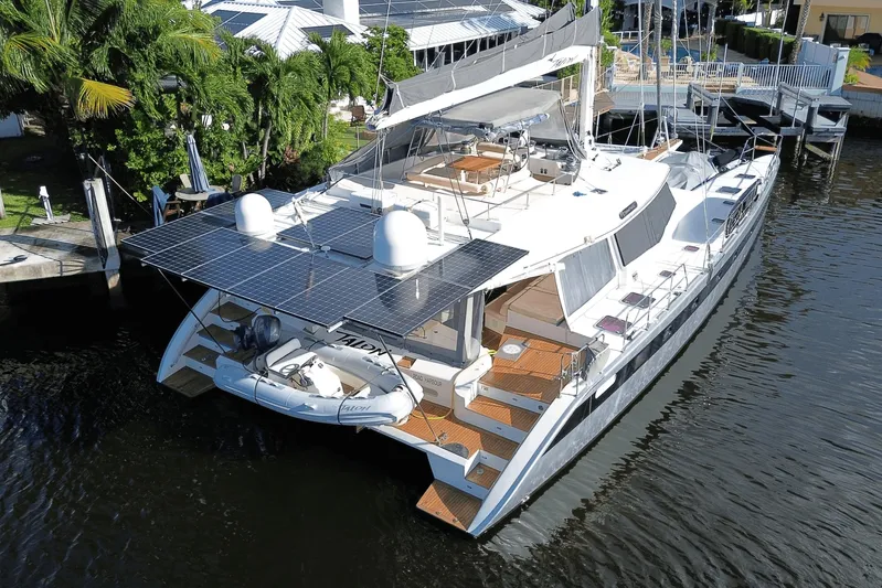 Talon Yacht Photos Pics Luxurious 2011 Sunreef 62 yacht with solar panels docked by lush greenery.