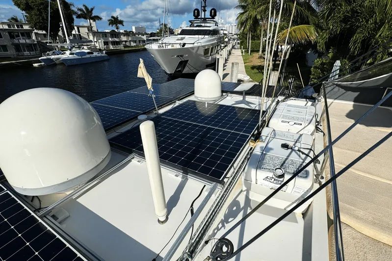 Talon Yacht Photos Pics 2011 Sunreef 62 yacht with solar panels docked by a canal, surrounded by palm trees.