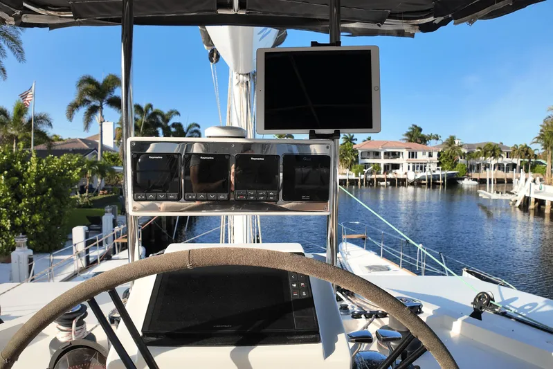Talon Yacht Photos Pics Steering wheel and navigation equipment on a 2011 Sunreef 62 yacht, docked by waterfront homes.