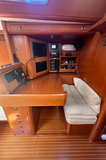  Yacht Photos Pics Navigation station in a 1999 Nautor Swan 68 yacht with wooden interior and cushioned seating.