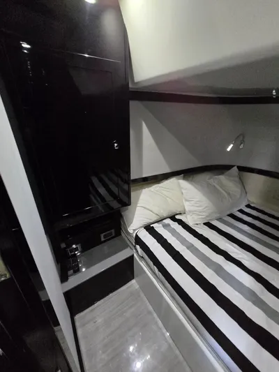 Lady Mash Yacht Photos Pics 2021 HCB 65 Estrella cabin interior with striped bedding and sleek black cabinetry.