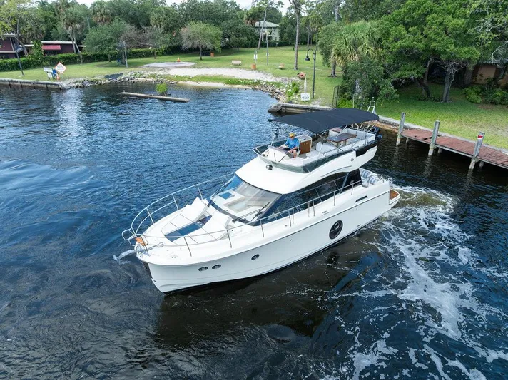 Have Another Yacht Photos Pics 2016 Beneteau Monte Carlo 4 yacht cruising on a serene waterway near a lush, green shoreline.