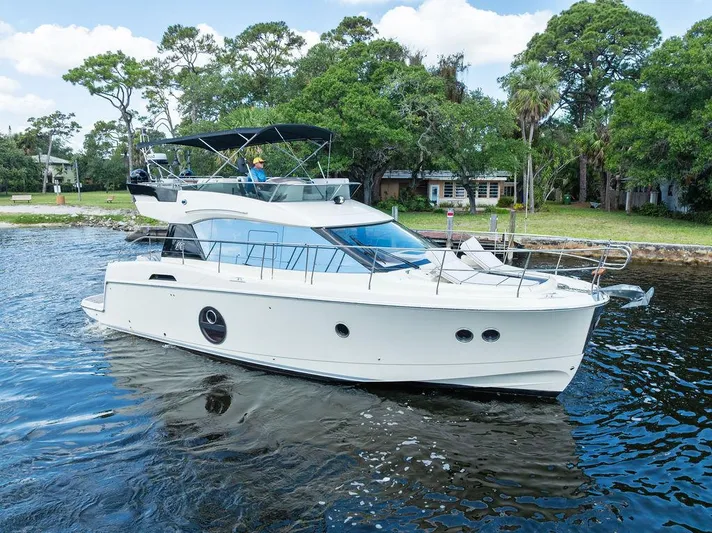 Have Another Yacht Photos Pics 2016 Beneteau Monte Carlo 4 yacht cruising on a serene waterway, surrounded by lush greenery.
