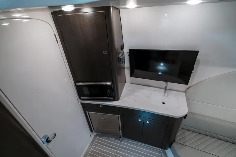 Tighten Up Yacht Photos Pics 2020 Intrepid 407 Panacea interior with kitchenette, TV, and modern cabinetry.
