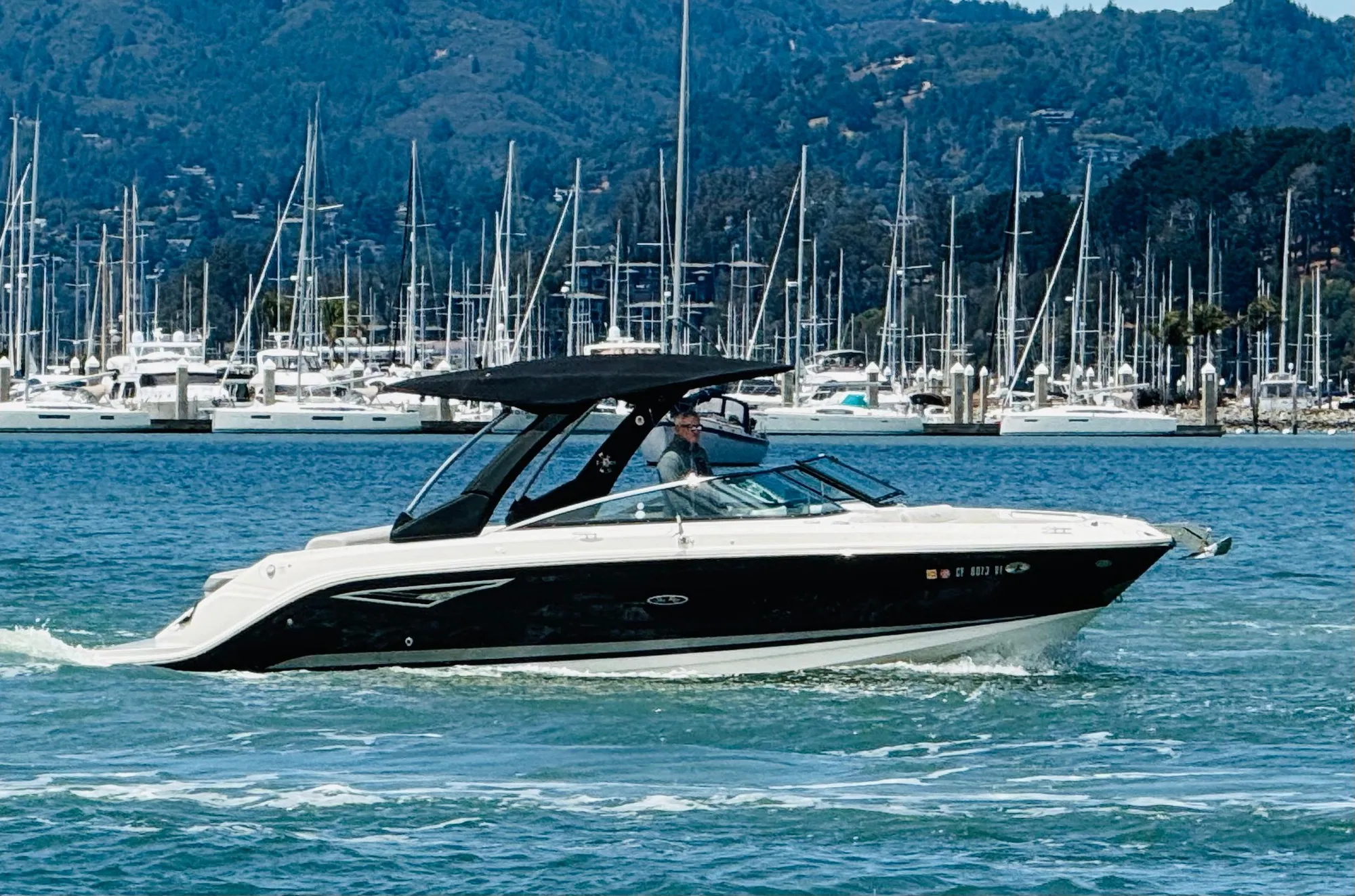 2020 Sea Ray SLX 280 boat cruising in a marina with mountains in the background.