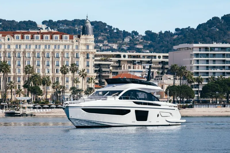  Yacht Photos Pics 2023 Azimut S7 yacht cruising near a coastal city with historic architecture.