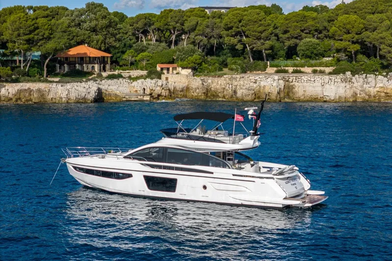  Yacht Photos Pics 2023 Azimut S7 yacht cruising near a rocky coastline with lush greenery.