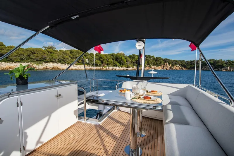  Yacht Photos Pics Luxurious 2023 Azimut S7 yacht deck with dining setup, overlooking serene coastal waters.