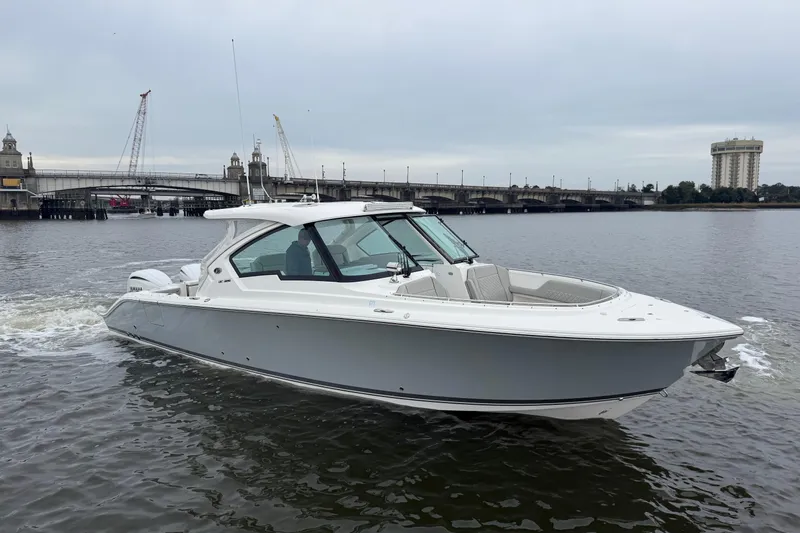  Yacht Photos Pics 2023 Pursuit DC 326 Dual Console boat cruising on a river near a bridge.