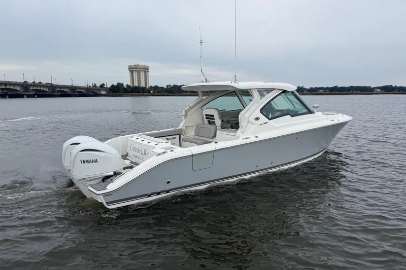  Yacht Photos Pics 2023 Pursuit DC 326 Dual Console boat cruising on a calm river near a bridge.