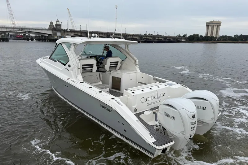  Yacht Photos Pics 2023 Pursuit DC 326 Dual Console boat cruising on a river near a bridge.